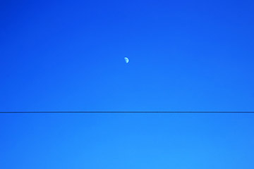 Minimalist photo by Phoresto Kim featuring a small half-moon and a horizontal line in the sky 특성이미지